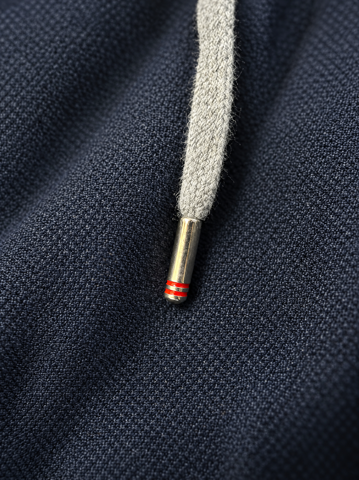 Kordelspitze aus Metall mit zwei roten Ringen auf dem Wolle-Kaschmir-Stoff
