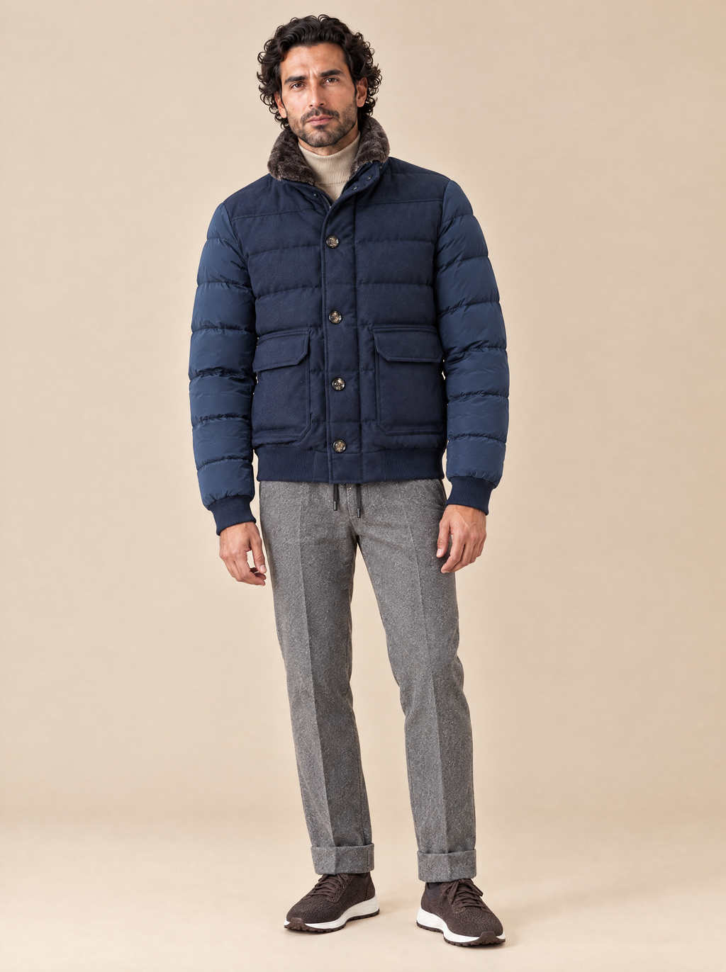 Moorer Steppjacke in Dunkelblau mit Lammfellkragen, getragen mit beigem Stehkragenpullover, grauer Kordelhose und braunen Sneakern