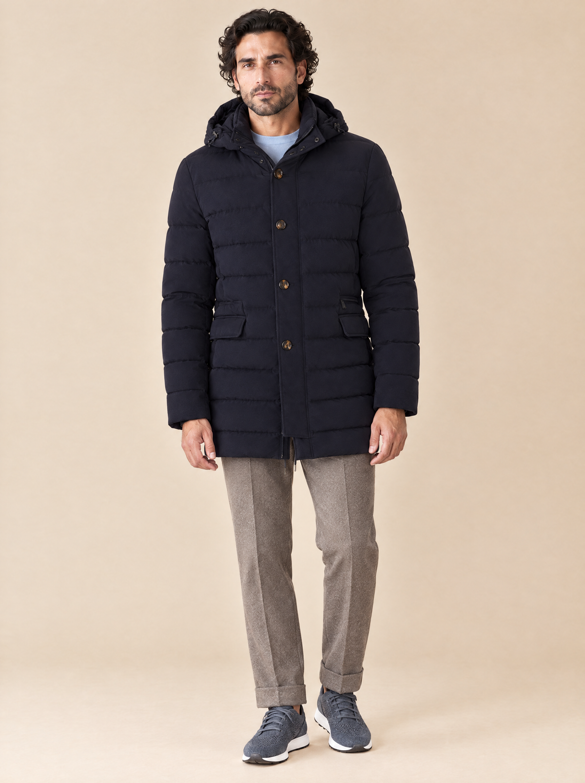 Moorer Daunenjacke Calandri in Dunkelblau, getragen mit hellblauem Rundkragenpullover, taupefarbener Kordelhose und blaugrauen Sneakern